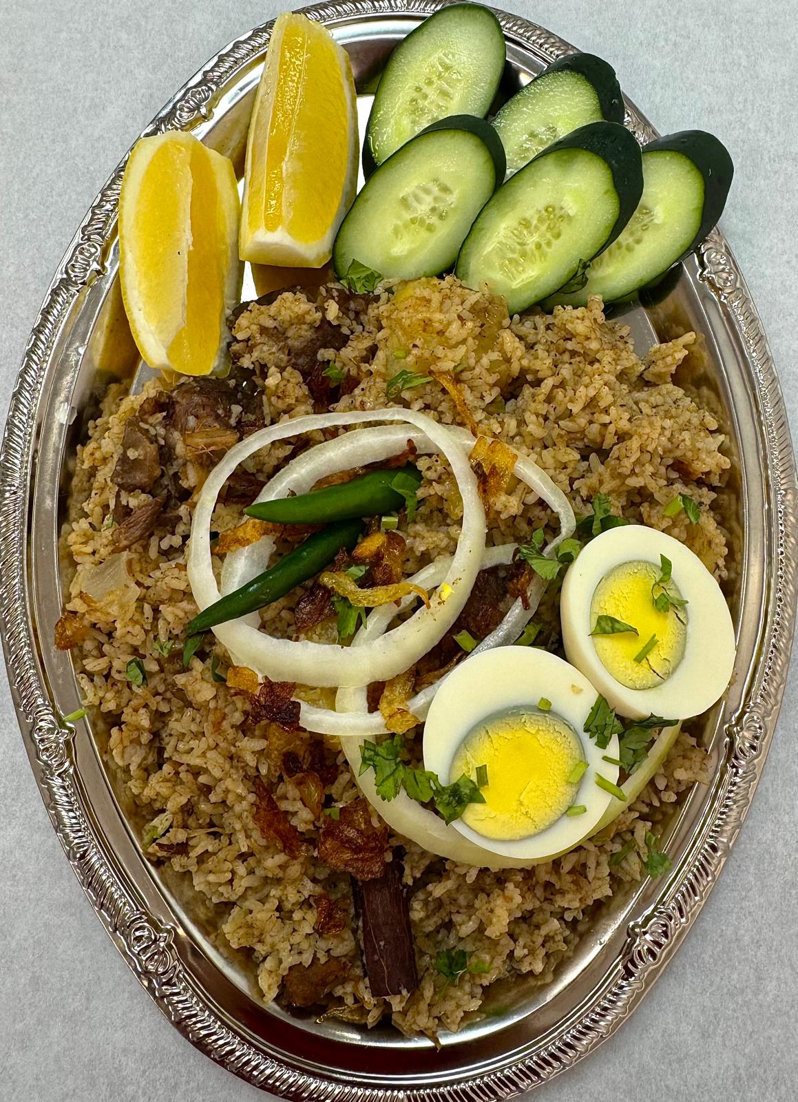 Full tray of Bengali beef tehari with crispy fried onions, boiled eggs, cucumber and lemon