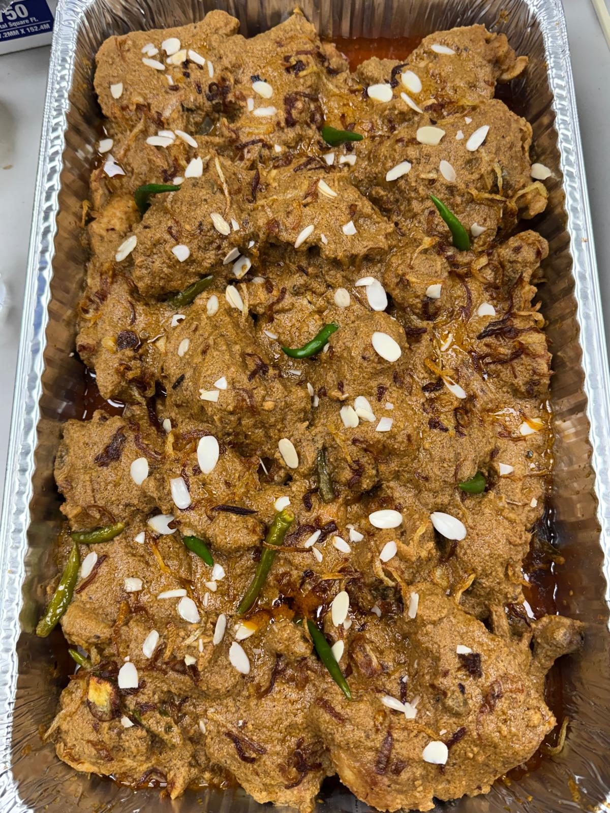 Full tray of chicken roast in creamy spiced gravy topped with slivered almonds and green chilies
