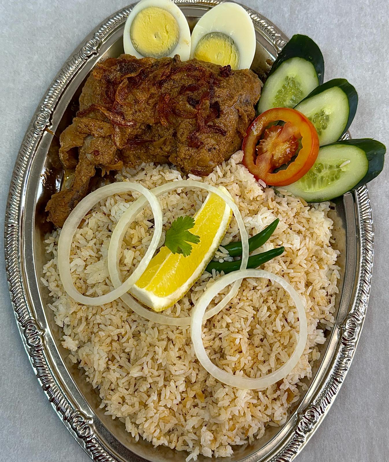 Full tray of Morough Polao with chicken roast, boiled eggs, cucumber and onion